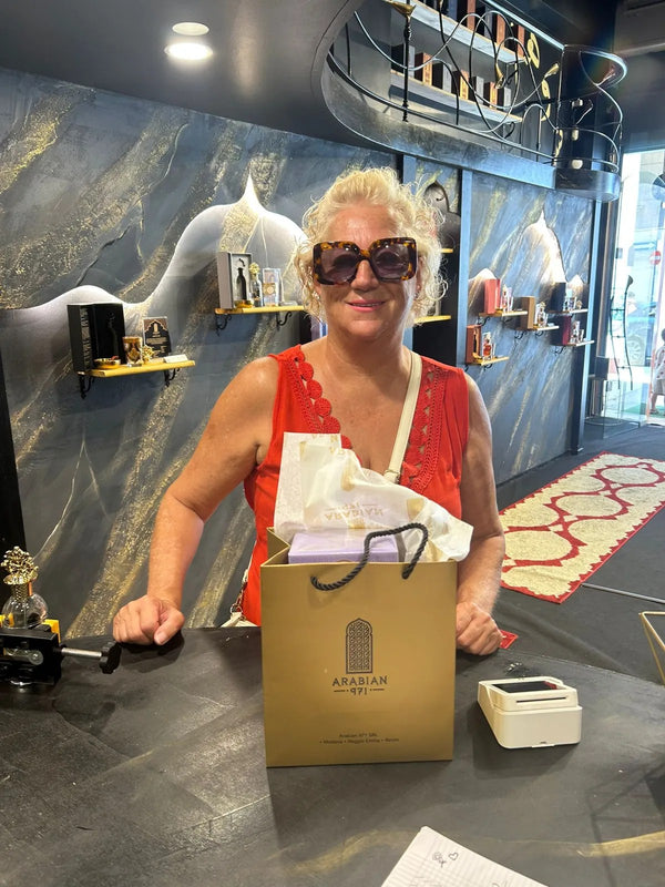 Una cliente al banco della boutique con la busta dorata Arabian 971.