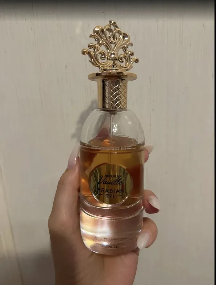 Il flacone di Arabian Vanille tenuto in mano, con il tappo dorato a corona.
